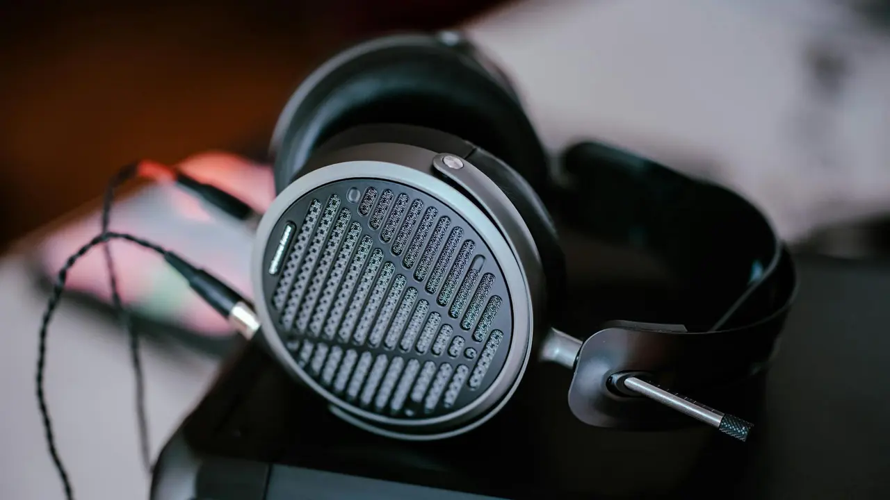 Elegancki zbiór wysokiej klasy słuchawek audiofilskich leżących na drewnianym stole, przygotowanych do porównania w rankingu dla melomanów.